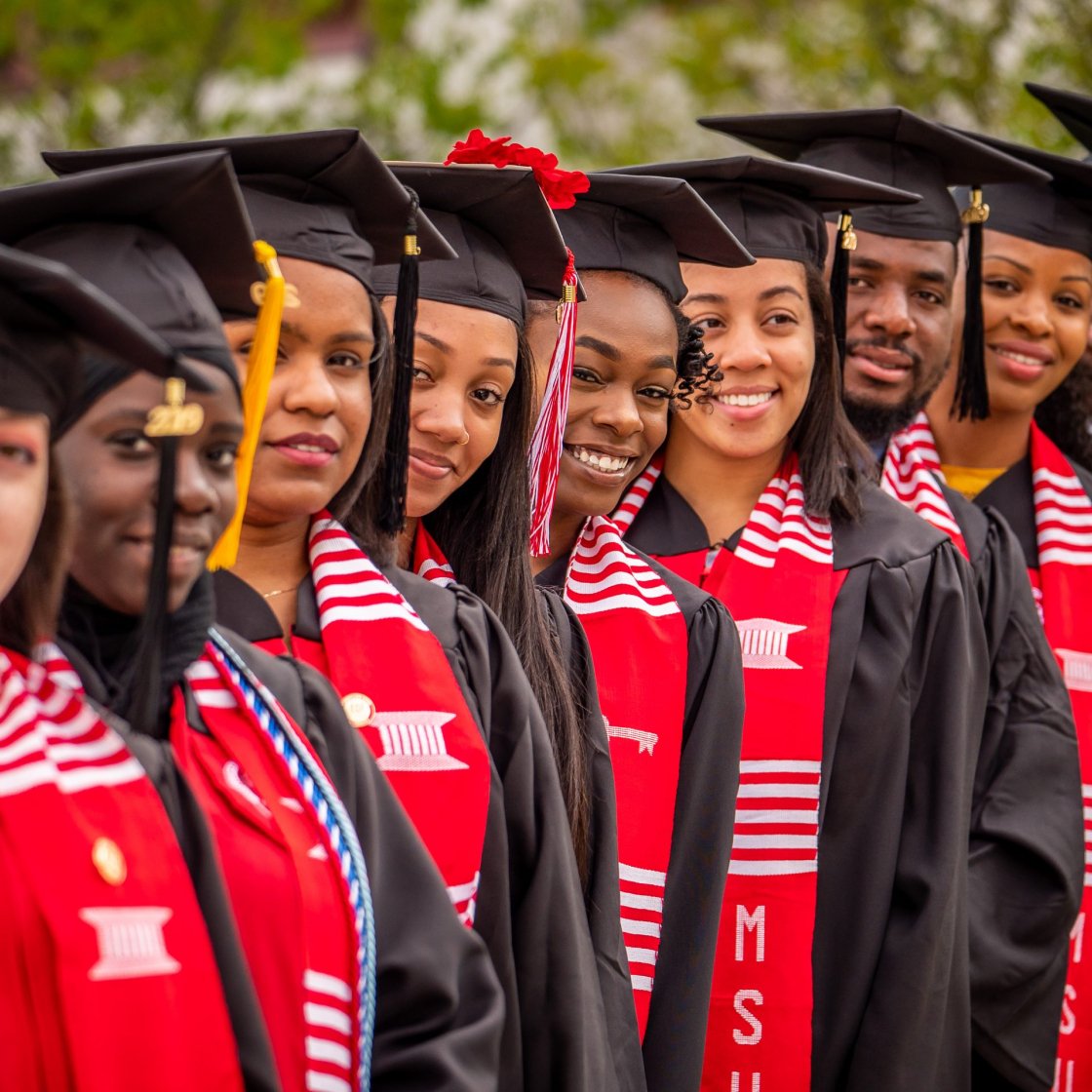 foreshortened view of a line of graduates in cap and gown with EOF shawl