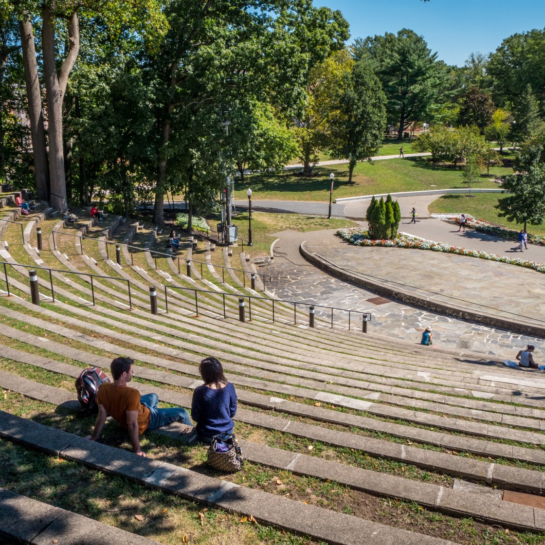 People sitting on tiered outdoor amphitheater seating on a campus