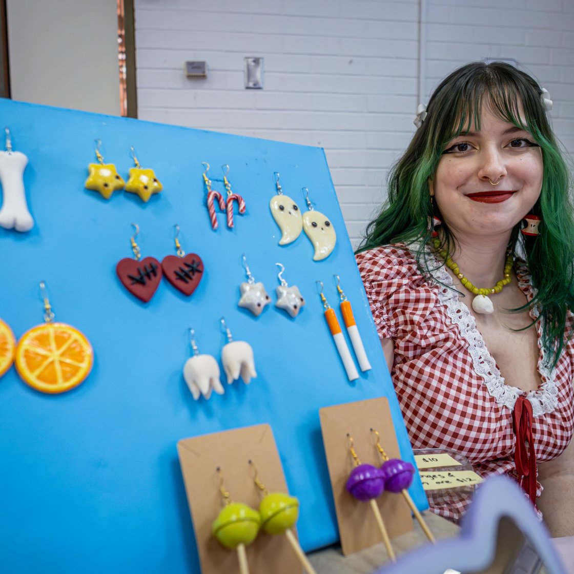 A female student smiling next to her earring display