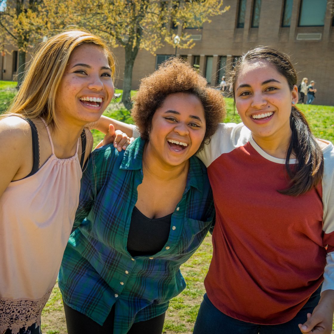 three students smiling in the quad
