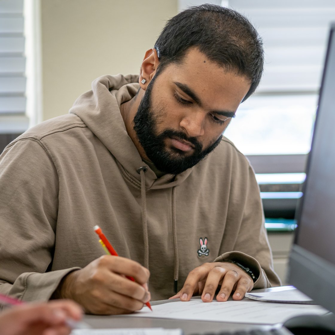Male student writing near a computer screen