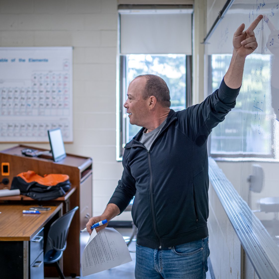 Male instructor pointing to white board