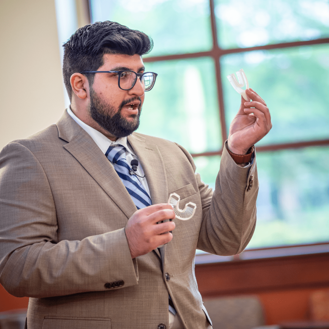 An MBA student holding a prototype of his flossing device at a pitch event