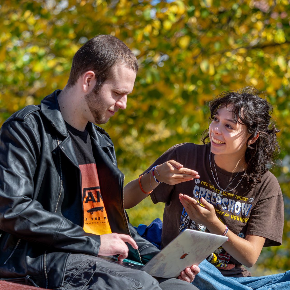 two students sitting outside talking to each other