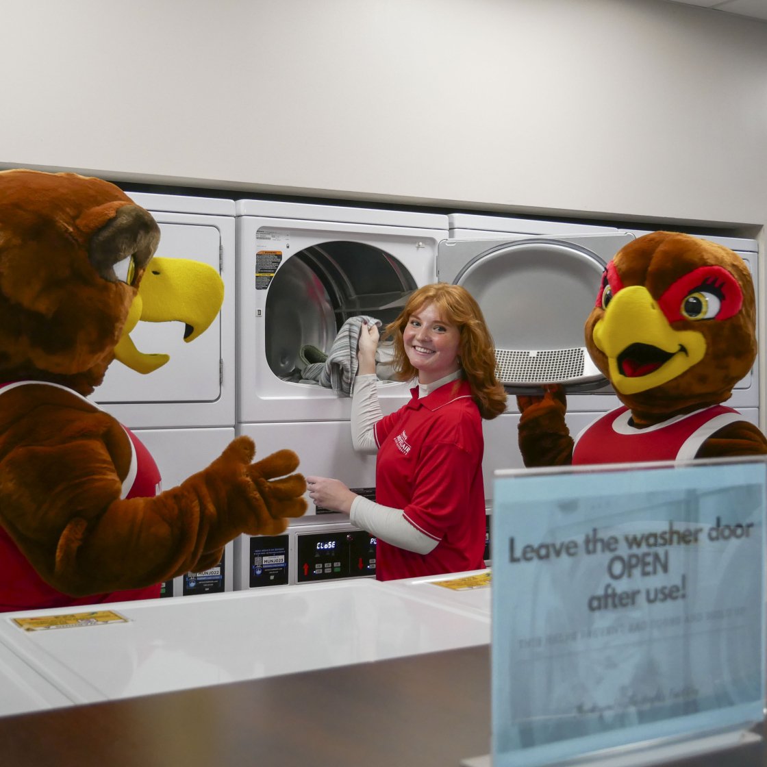 Rocky and Roxy doing laundry with a student in a residence hall