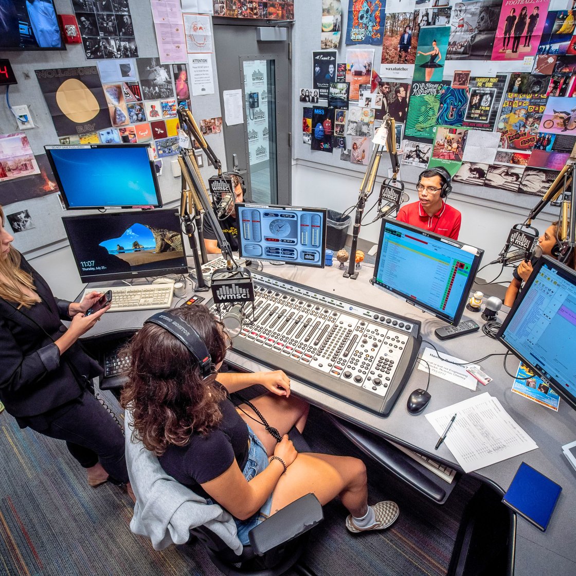 Students on air in broadcast studio.