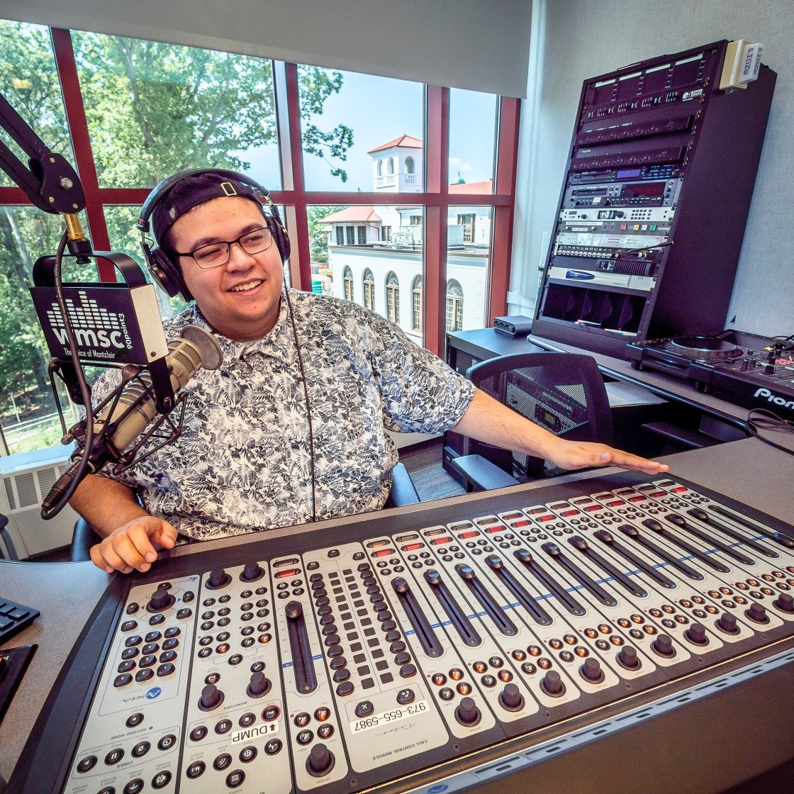 Student in podcast room manning the soundboard.