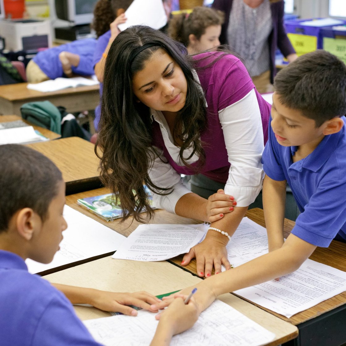 a teacher helps 2 students with their work