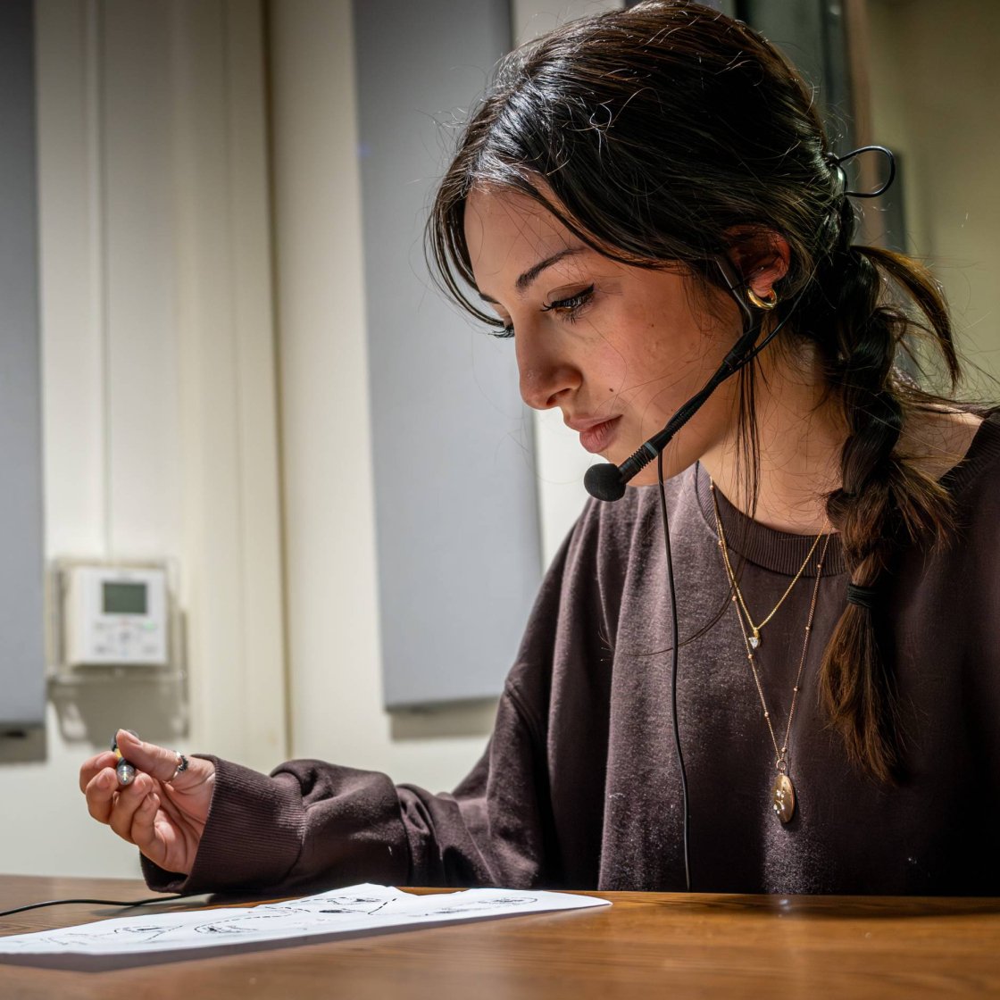 A student wearing a headset with microphone and reading a paper