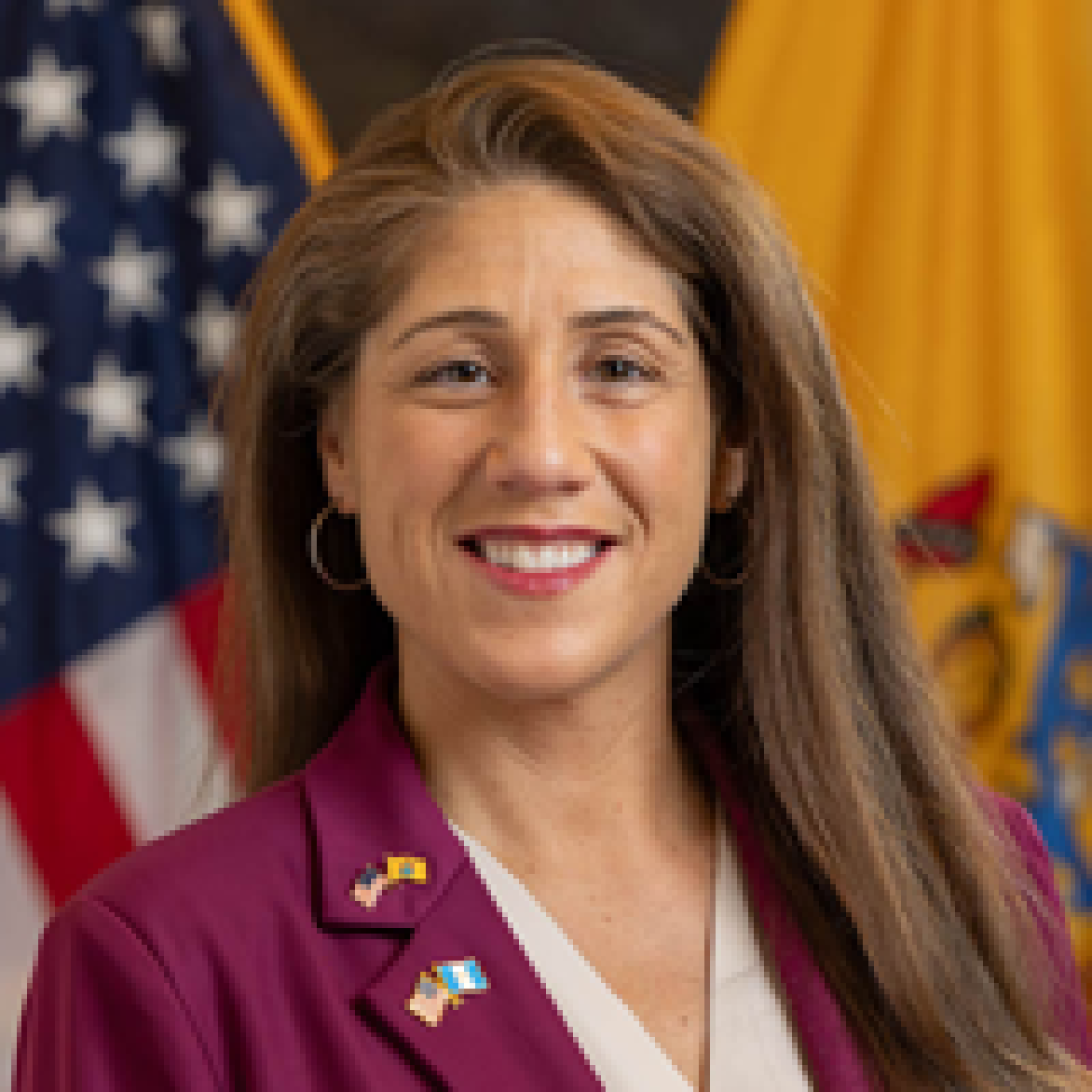 headshot of Acting Secretary of Higher Education Margo Chaly Esq. in front of American flag