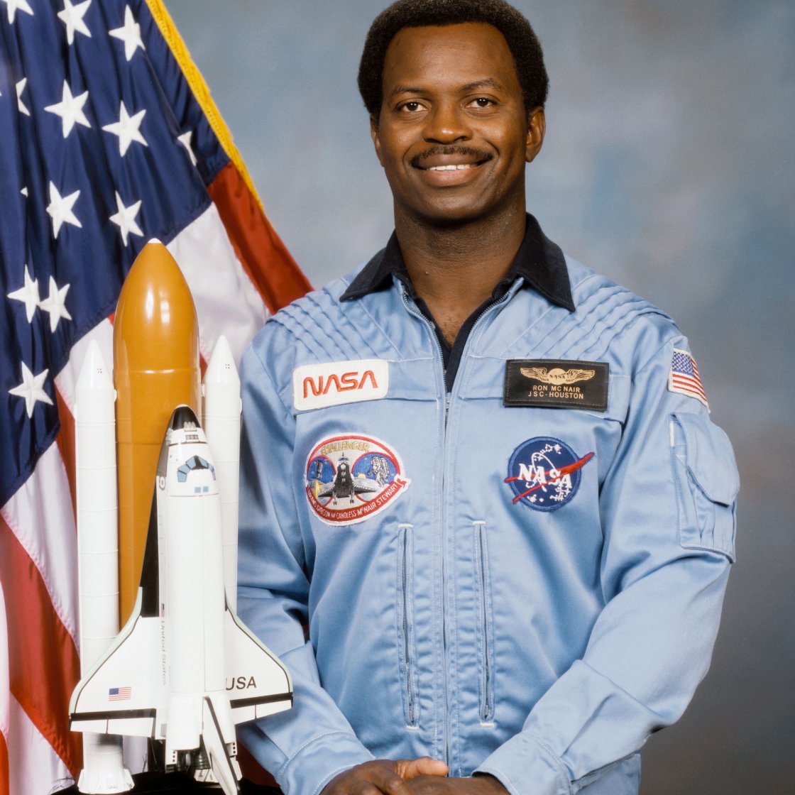 Male astronaut standing near American flag
