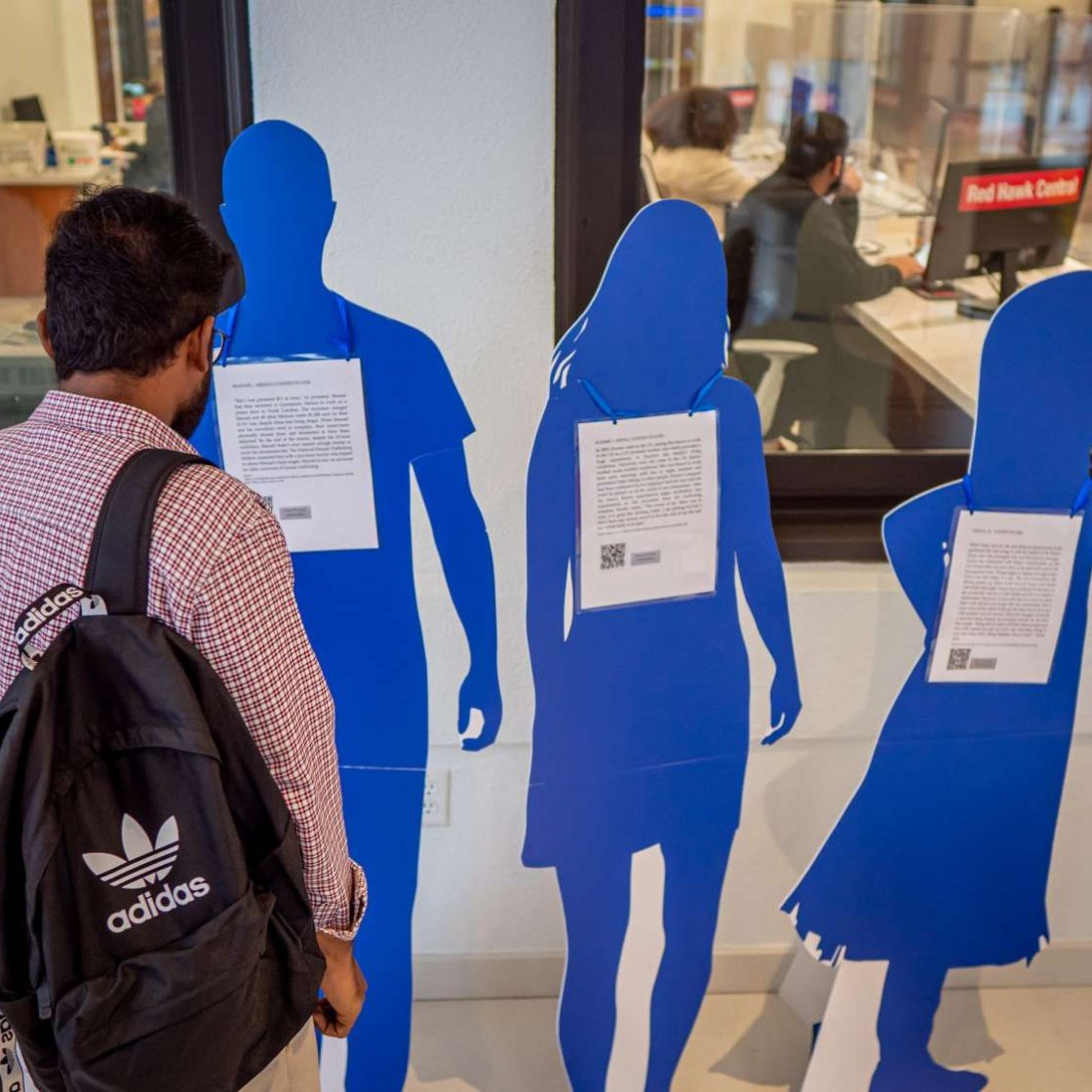 Student reading the personal trafficking stories of the "Blue People" on campsu