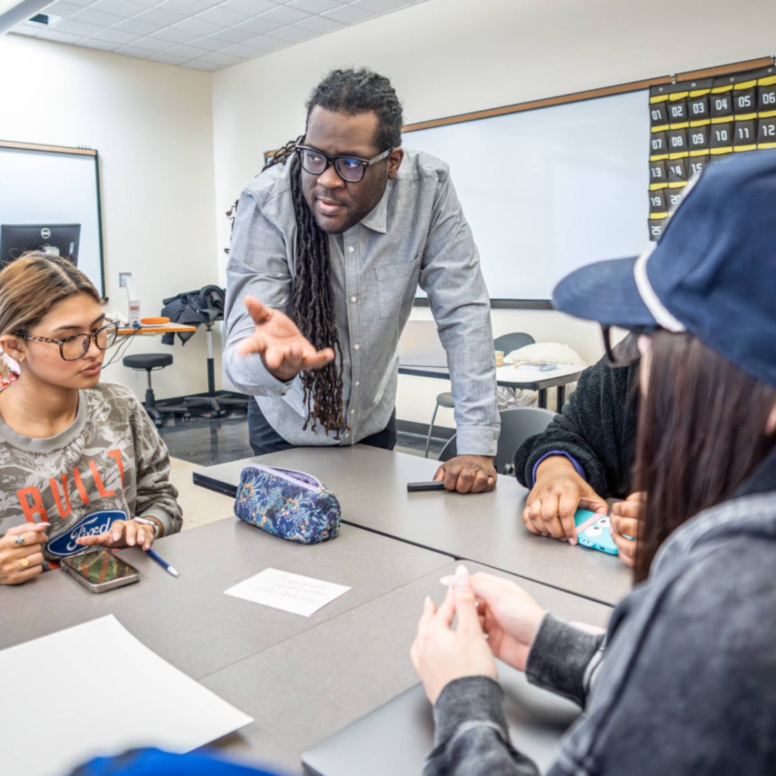 A college professor speaks to a breakout group of students in his class