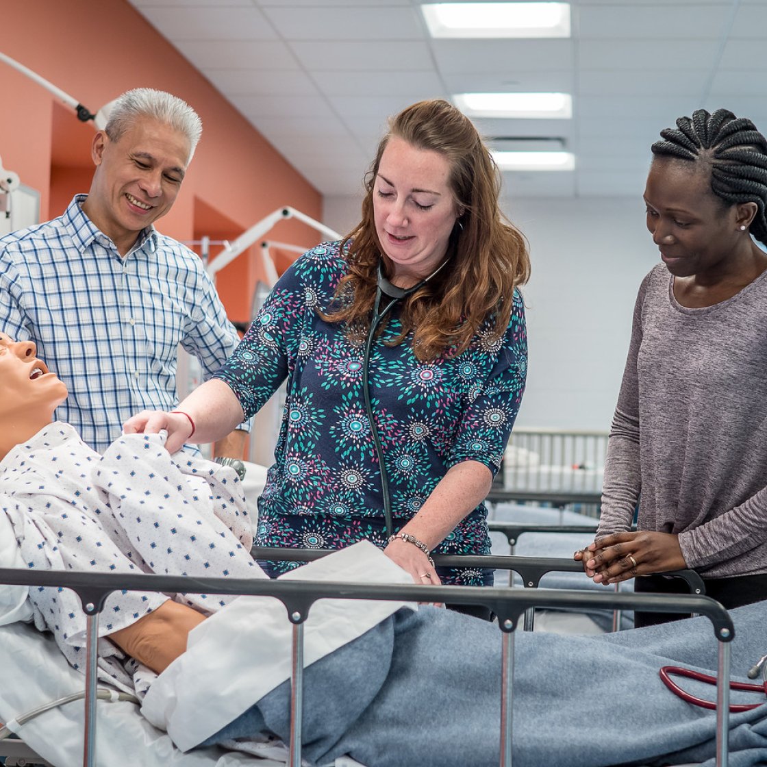 Students monitoring vitals on a patient care manikin.