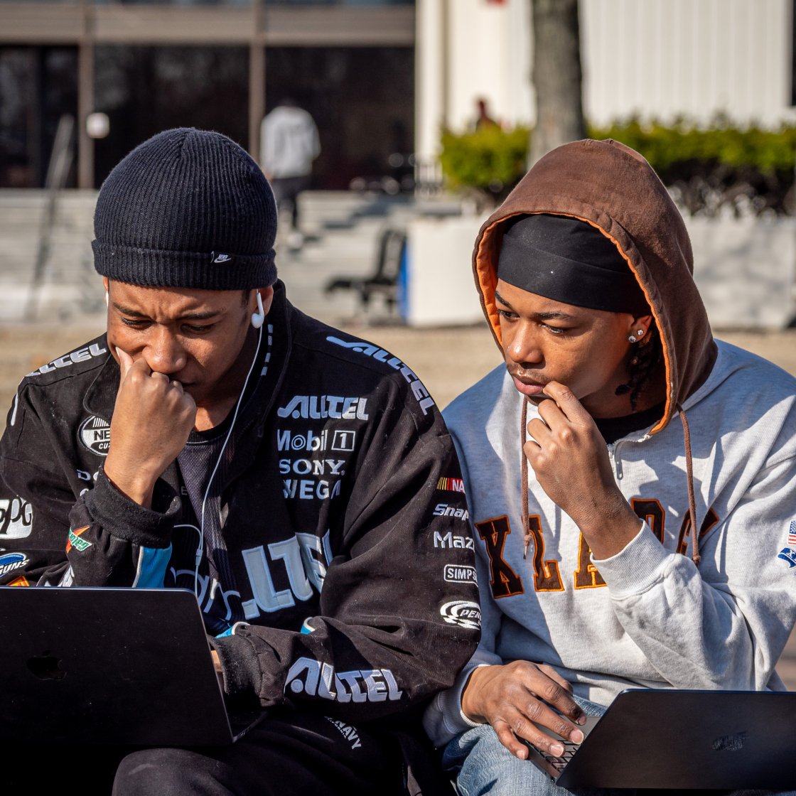 two students on the quad on their laptops 