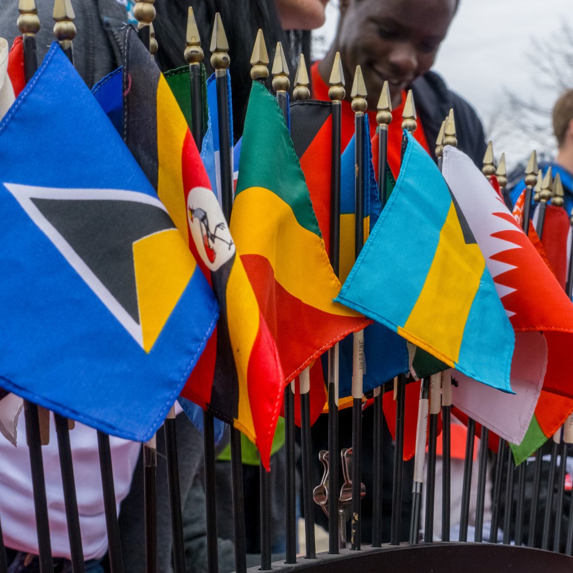 A group of flags from around the world with some students in the background.