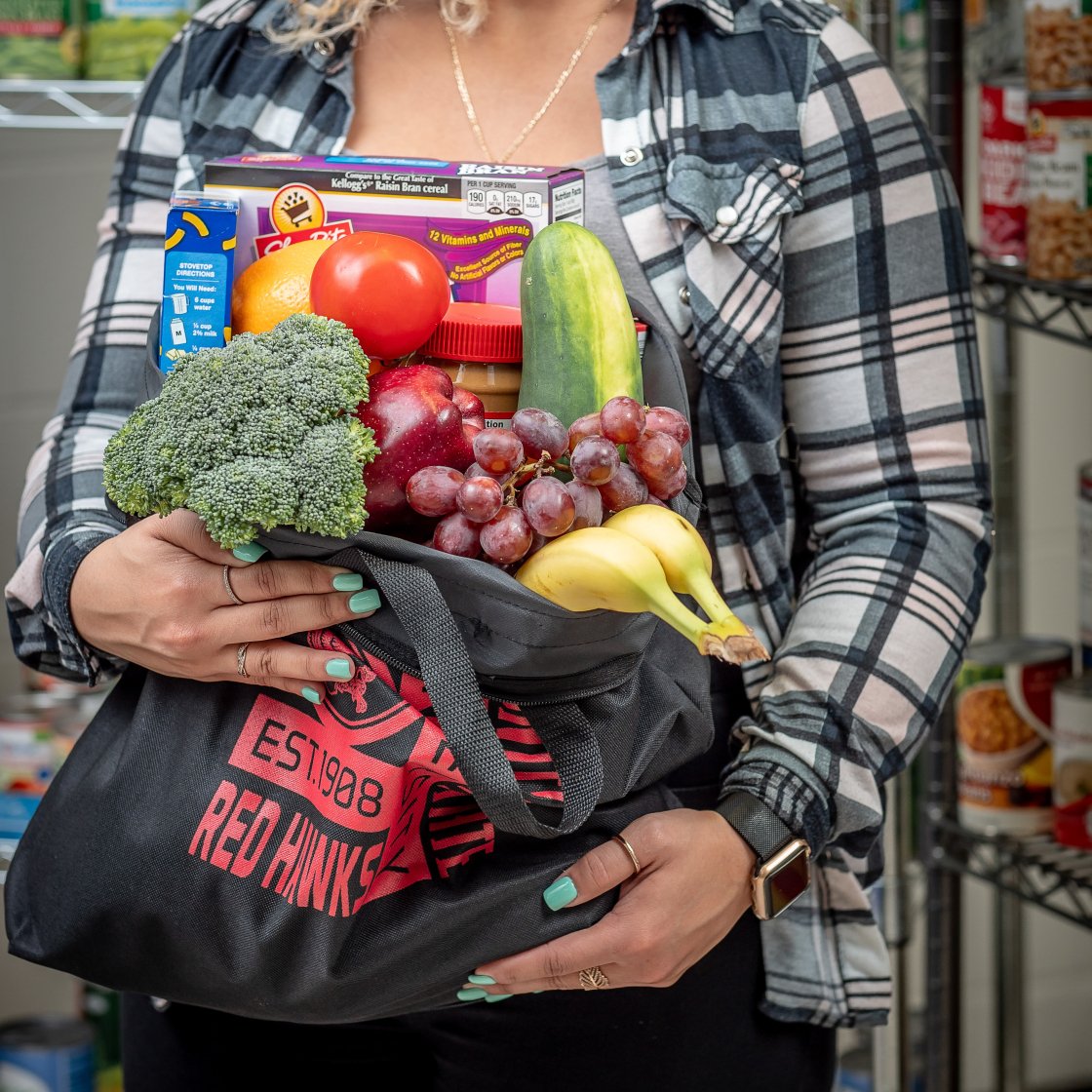 student holding tote bag full of fruits and veggies