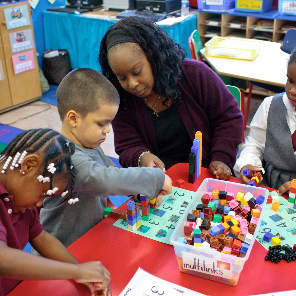 a teacher shows 3 kids how to do math