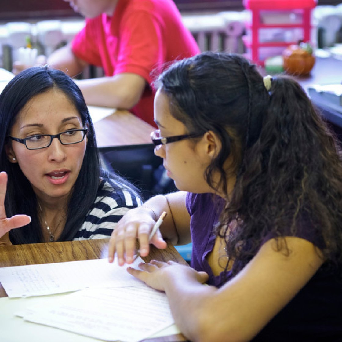 a teacher helps a student at her desk