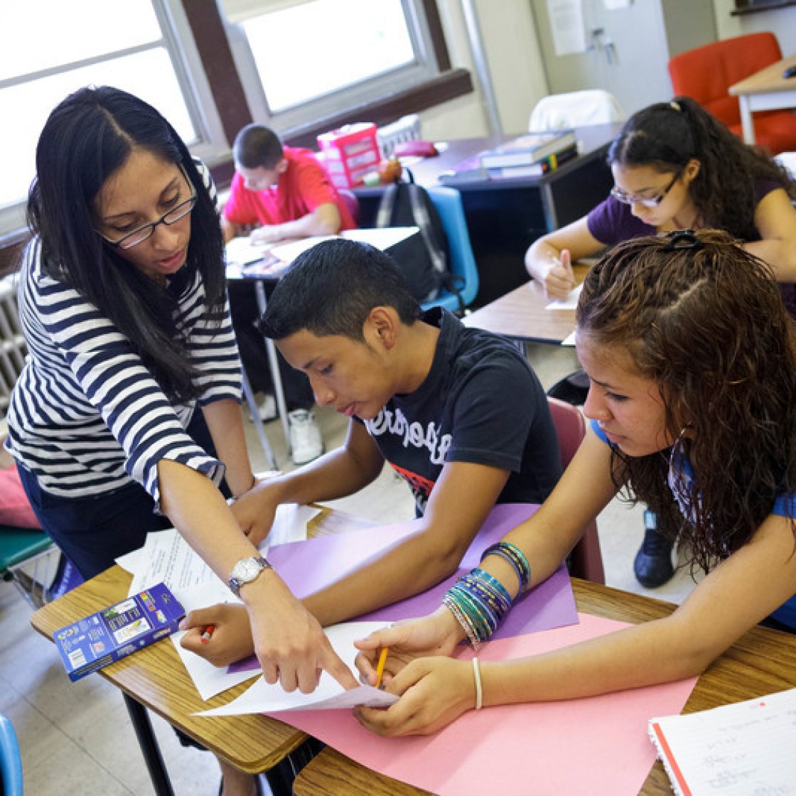 a teacher helps two kids in her classroom