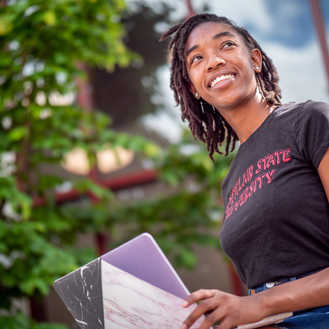 student sitting with a laptop outside