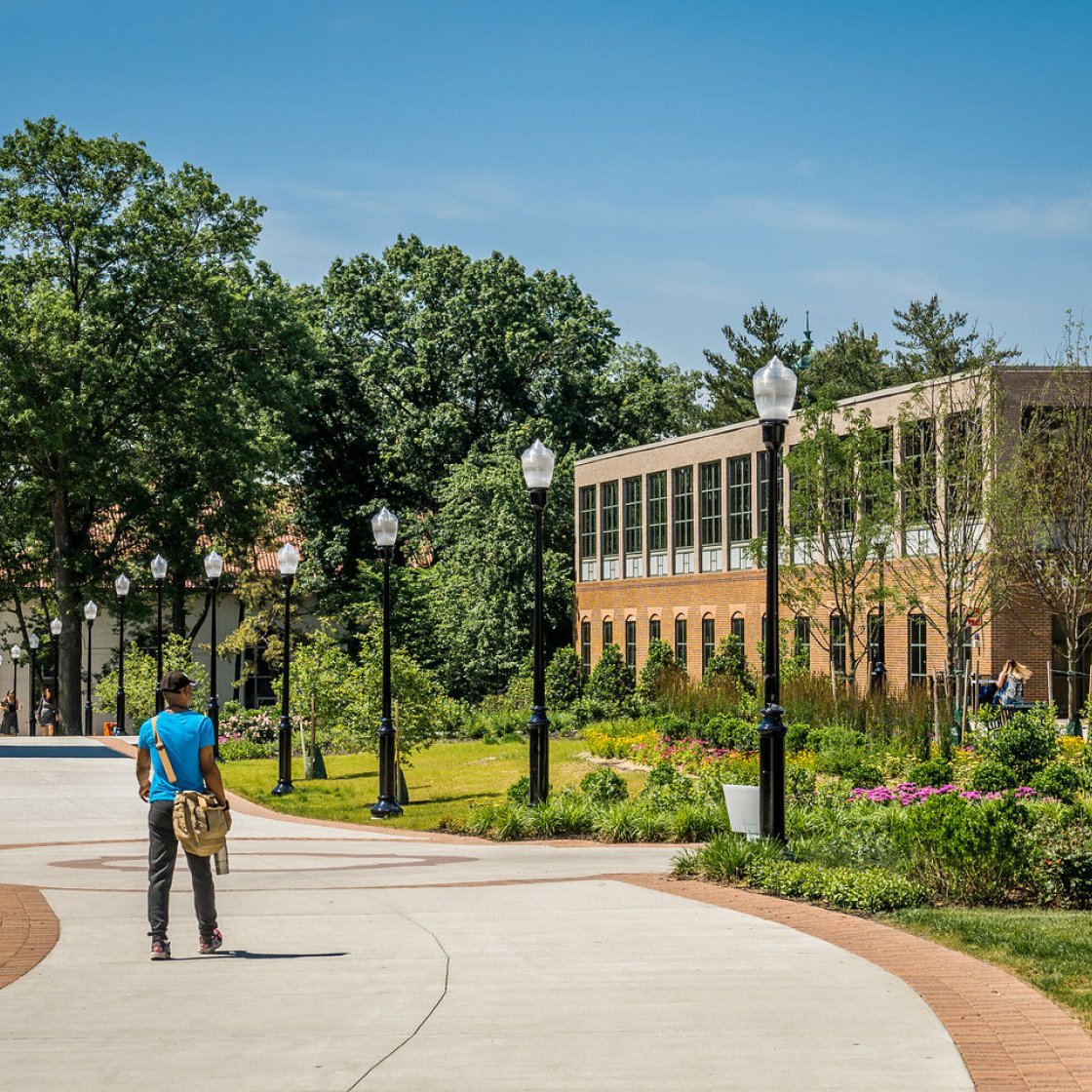 student on campus walkway by library
