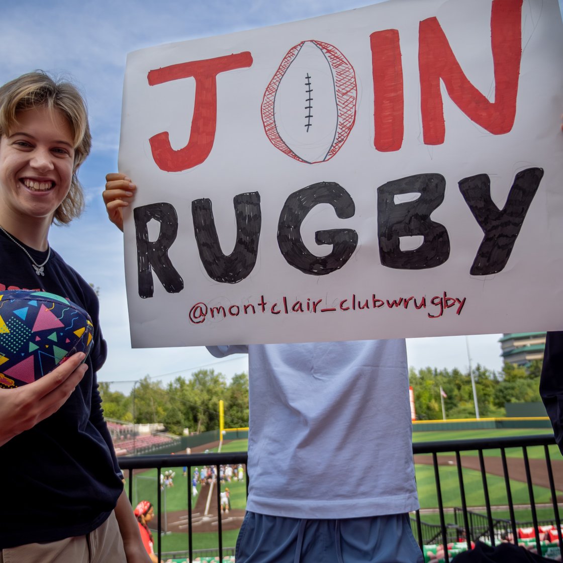 student pointing at a join rugby sign