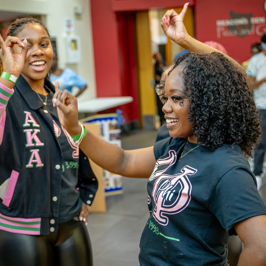 two greek aka students with pinkies up