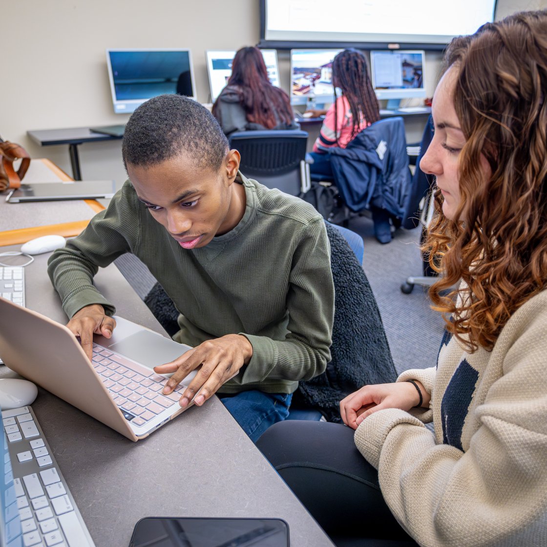 two IAC students work at a desk