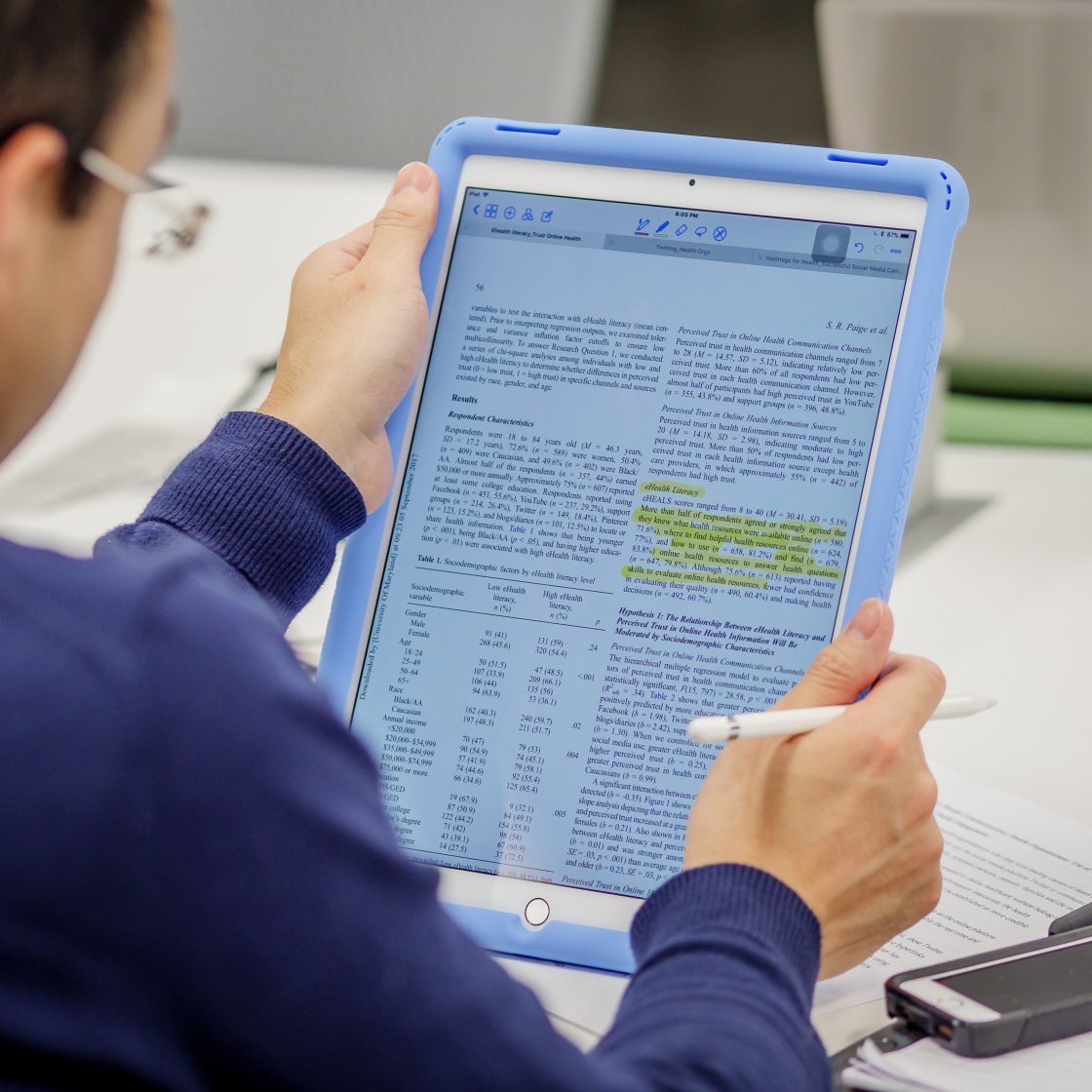Close-up of student reading research on tablet.