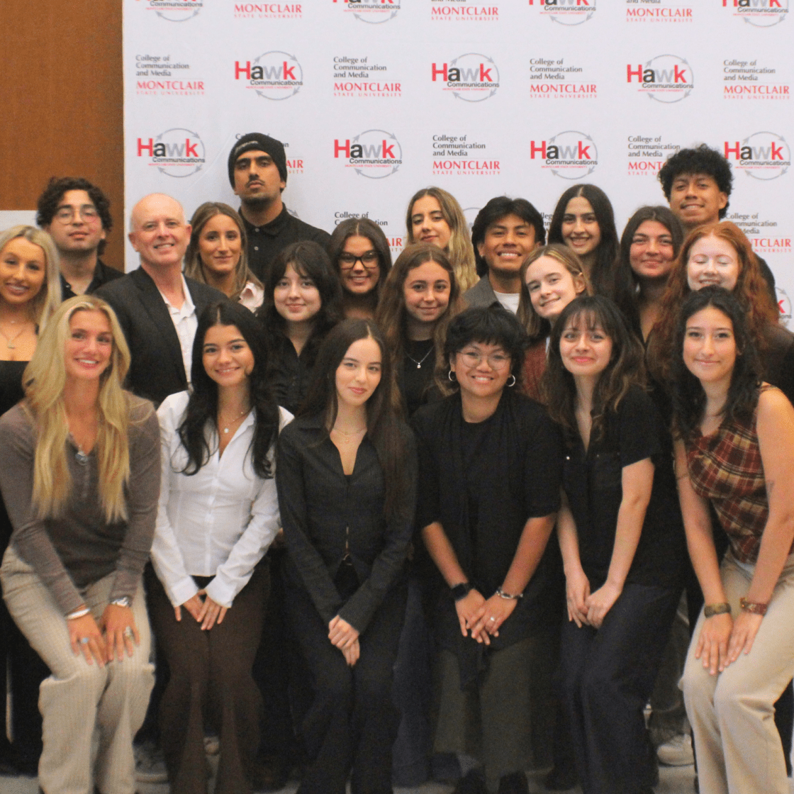 2025 cohort for Hawk Communications course posing in front of the CCOM step-and-repeat in the CCOM lobby.