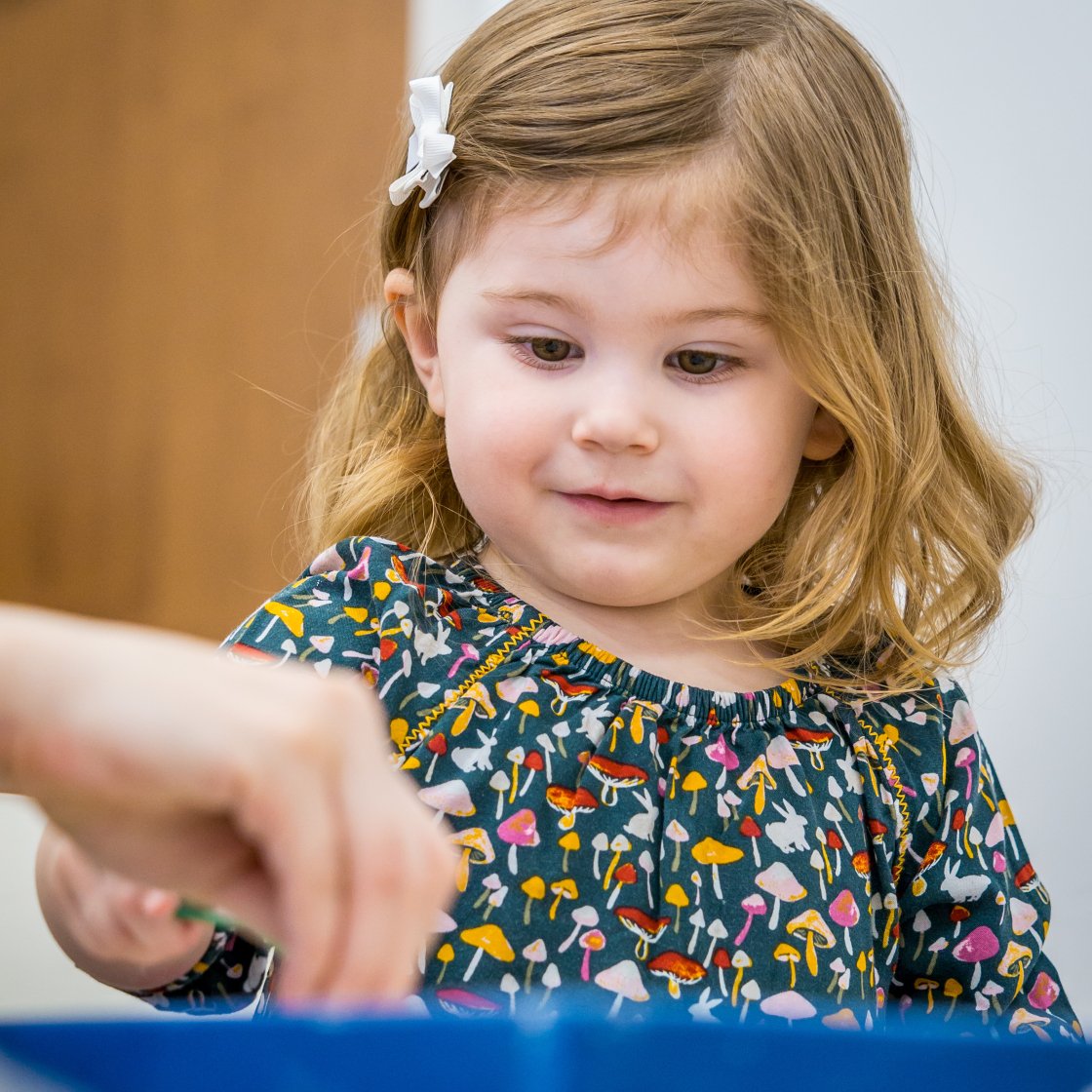Child smiling in front of sandbox