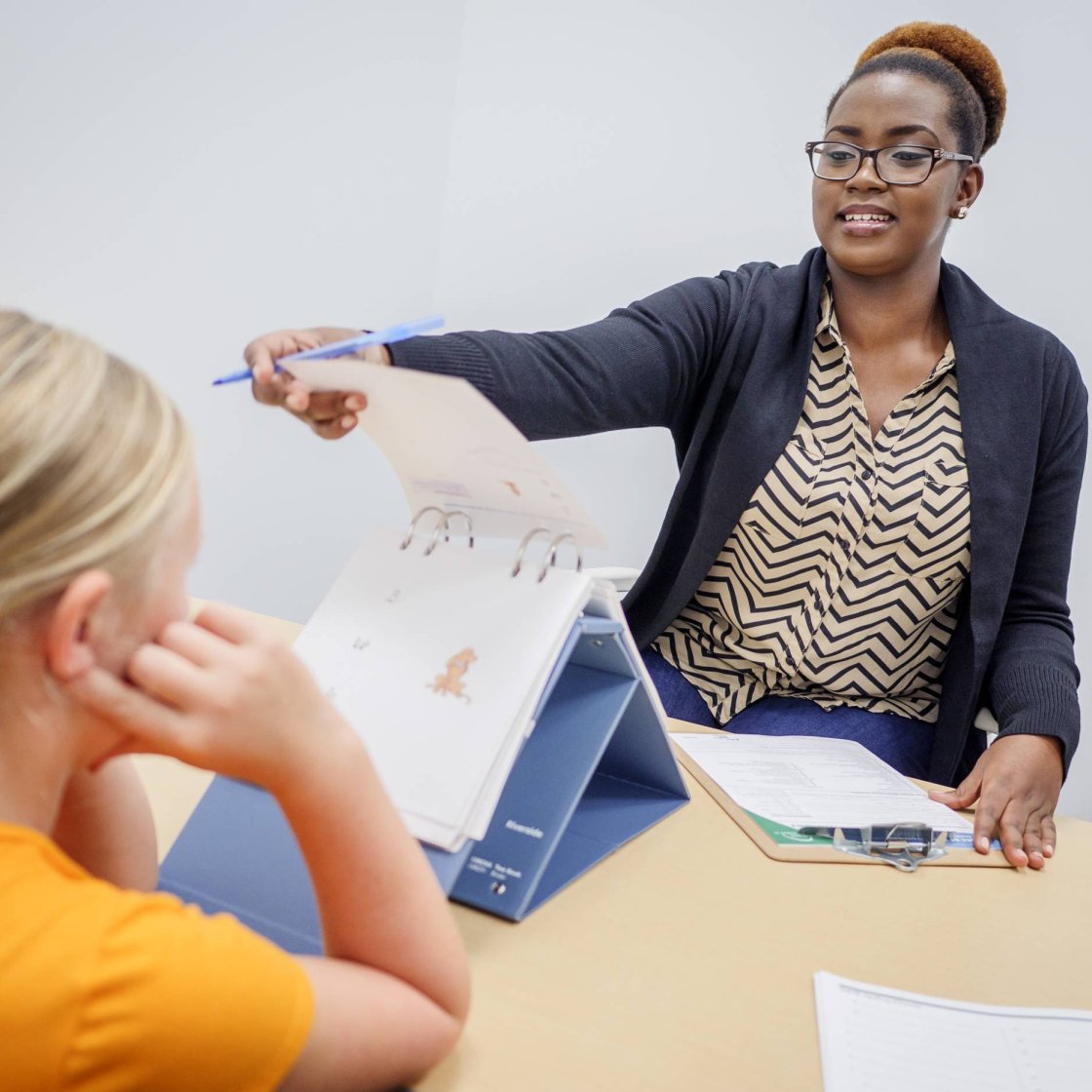A woman flips a page on a presentation as a student watches