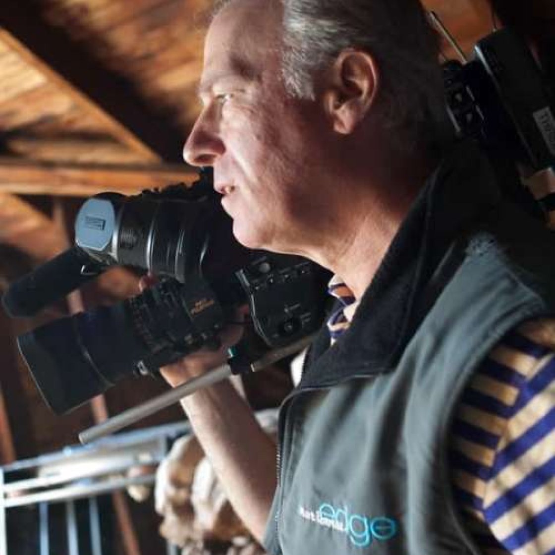 photo of Kenneth Browne looking away from camera, holding a large video camera on his shoulder