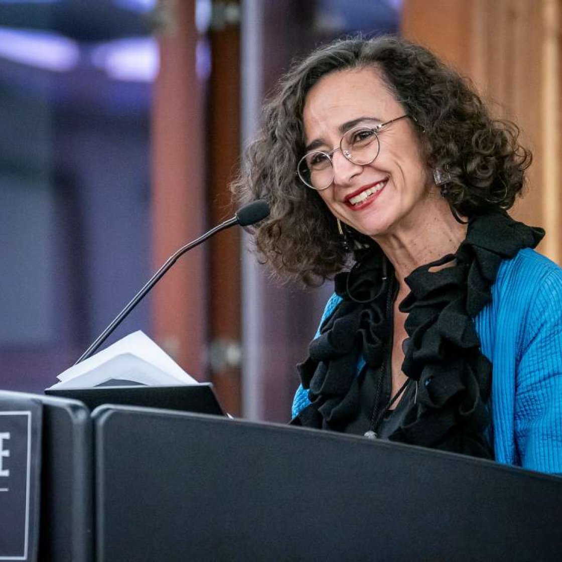 Photo of Teresa Fiore standing at podium smiling and speaking at podium