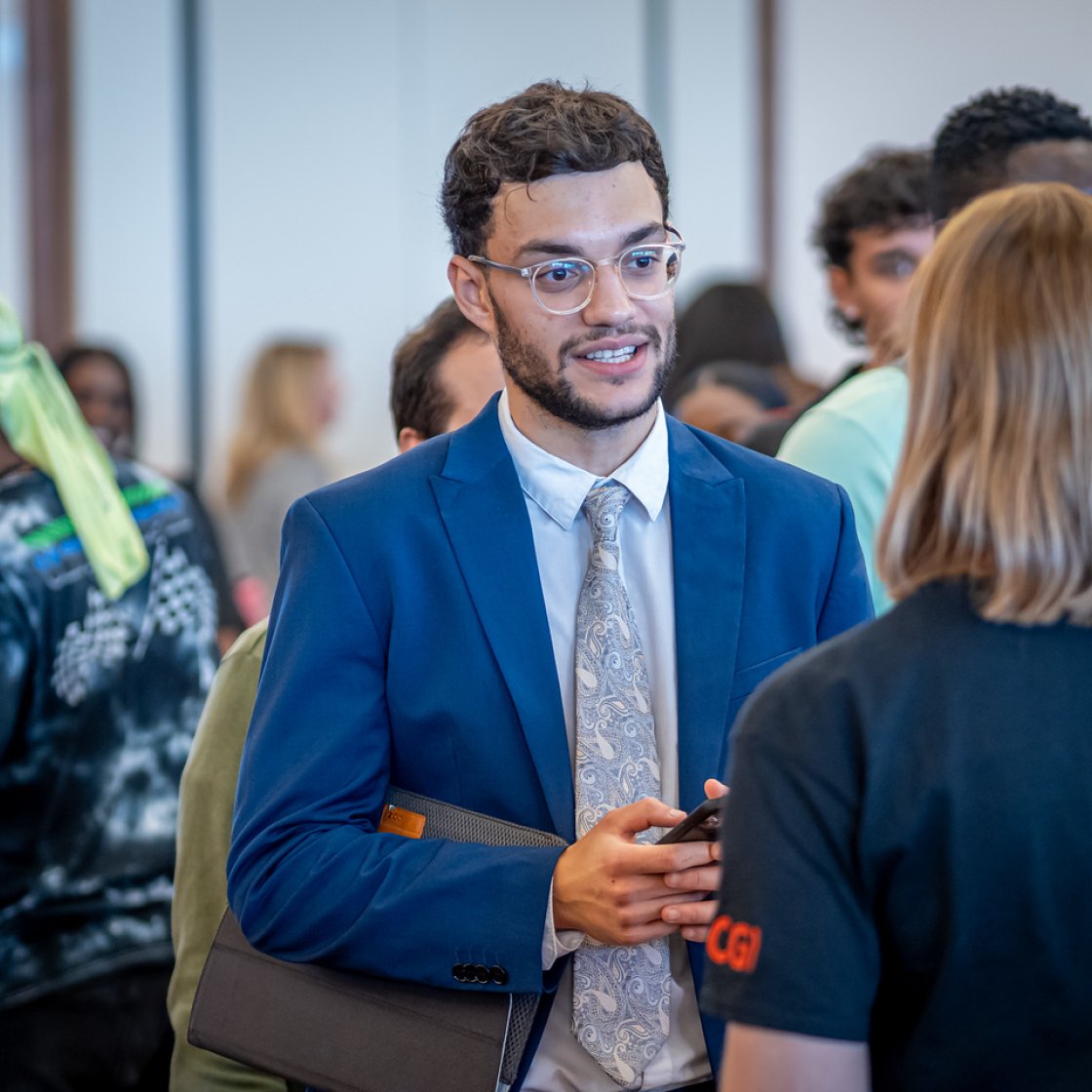 Student wearing a suit networks with an employer at a Career Fair.