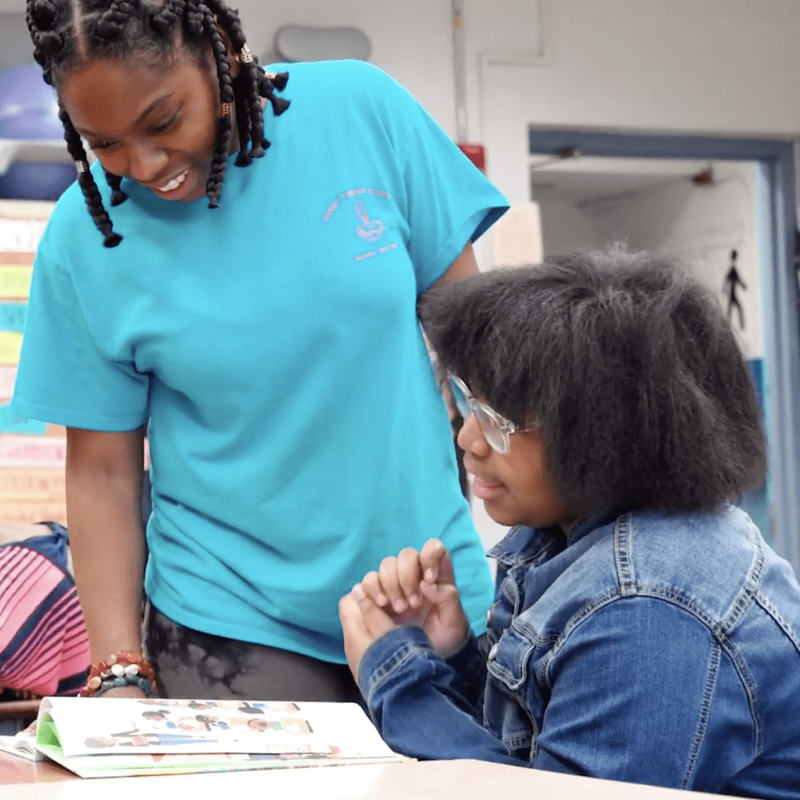 a teacher stands at a child's desk
