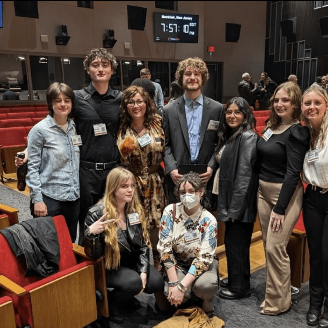 Group of students and professors posing for a photo in Presentation Hall.