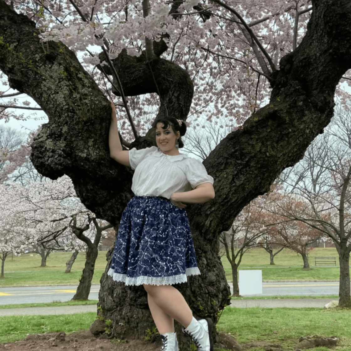 Ella Cavanagh posing in front of a cherry blossom tree