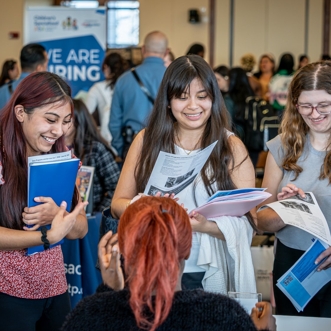 Students review informational materials and speak with representatives at a campus career fair while exploring internship and employment opportunities.