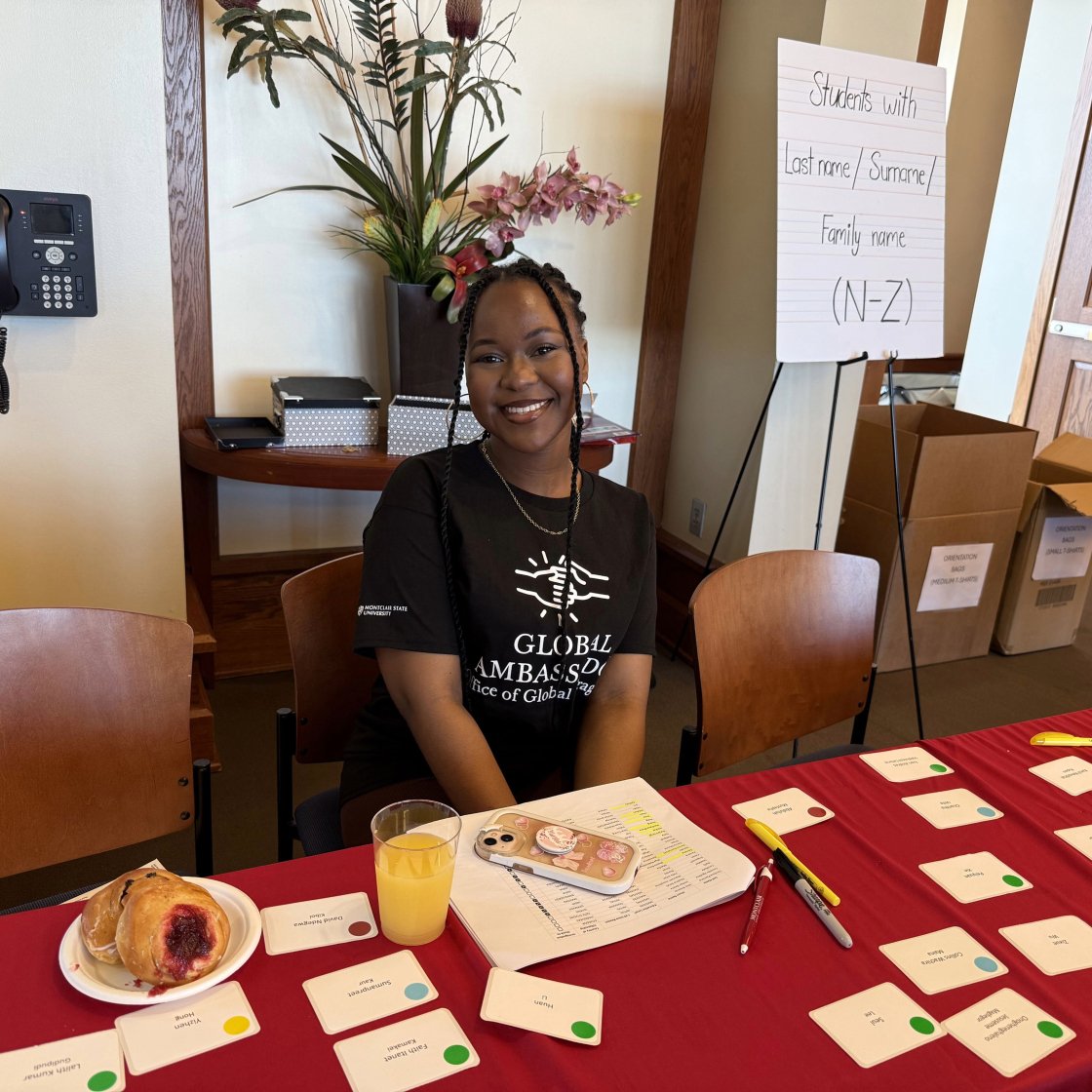 A picture of a global ambassador sitting at the check-in table at international student orienation.