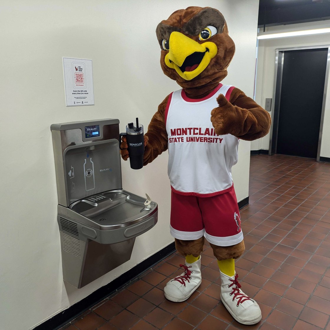 Mascot Rocky standing next to a water bottling filling station with his reusable bottle, giving a thumbs up, with the Fill it Forward QR code posted next to him.