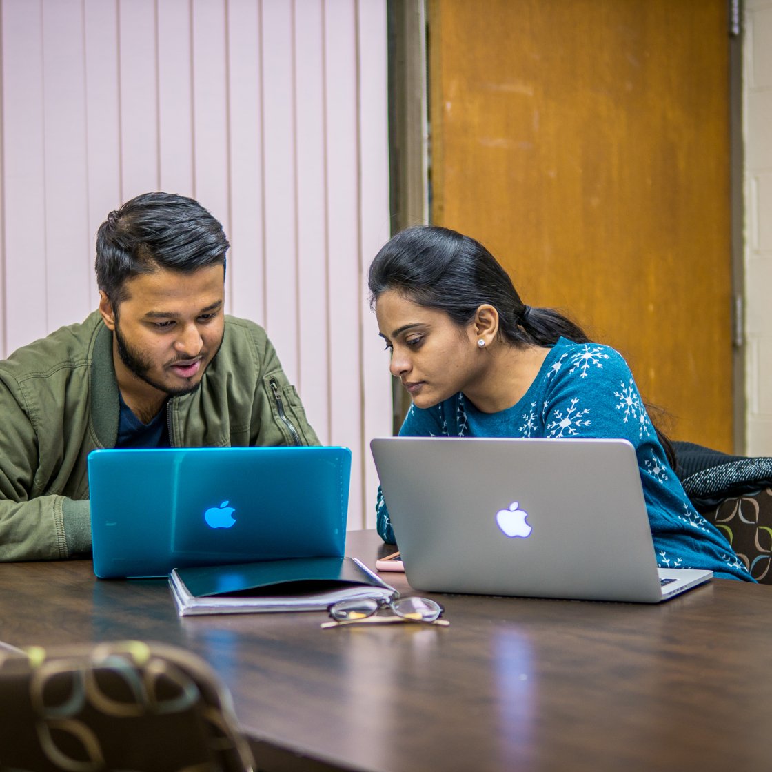 two students sit in front of laptops