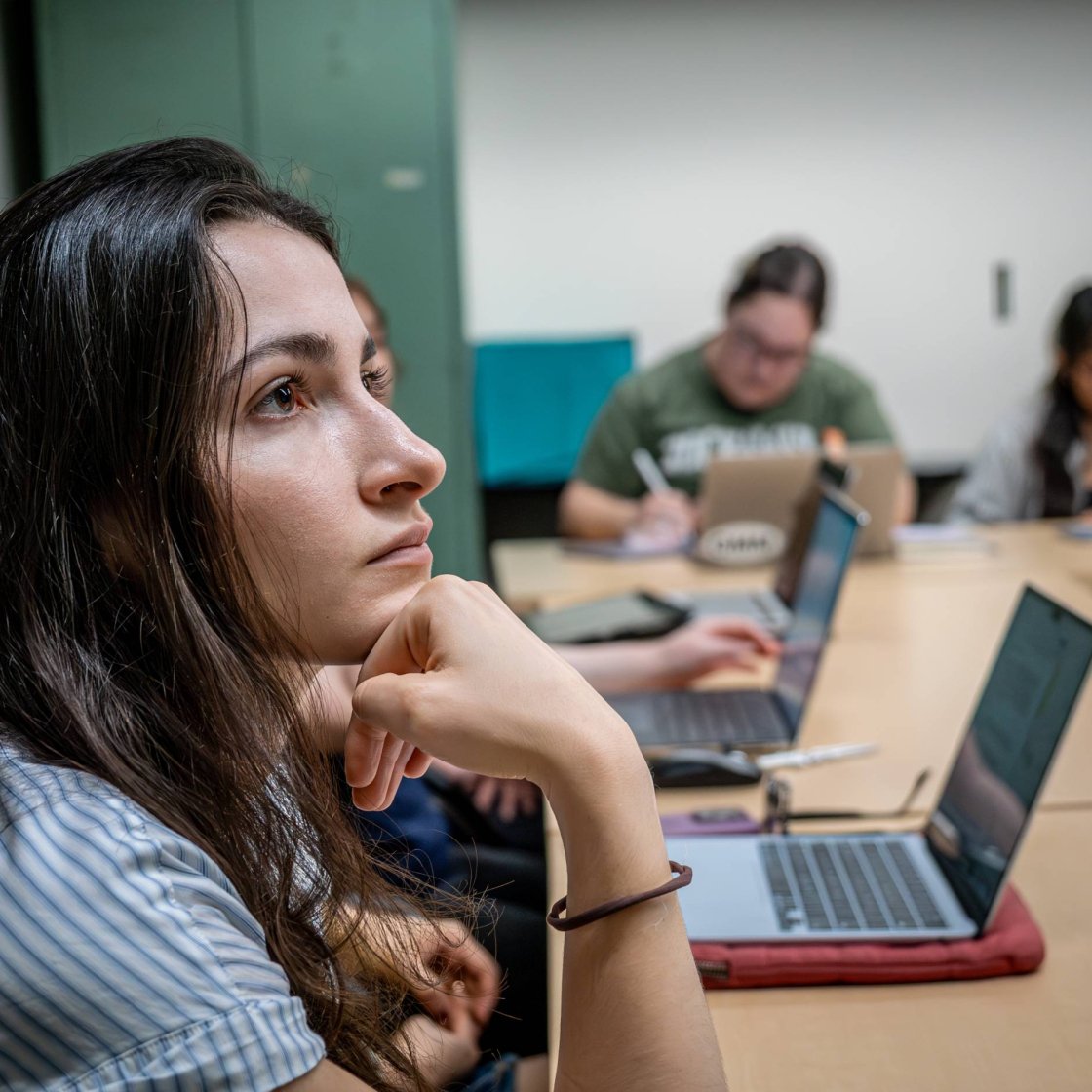 A college student sits in a clasroom and focuses on speaker