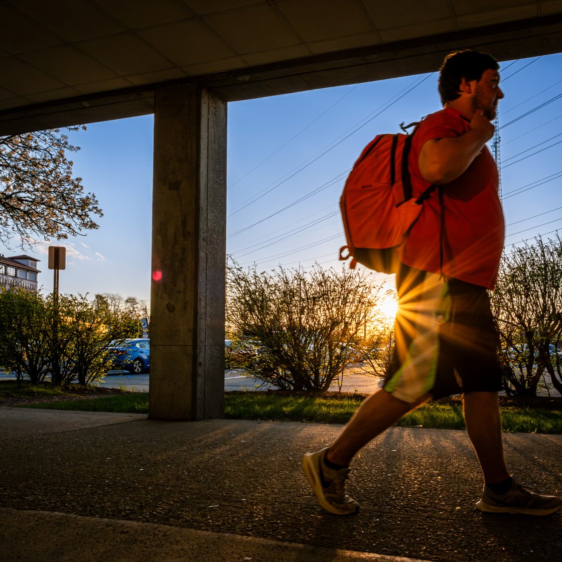 student walking with a backpack at sunset