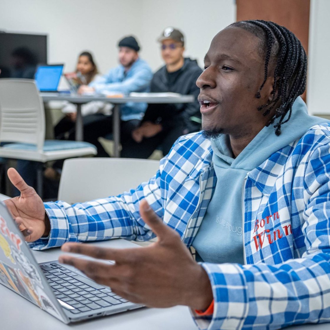 A college student sits in a classroom and answers a question