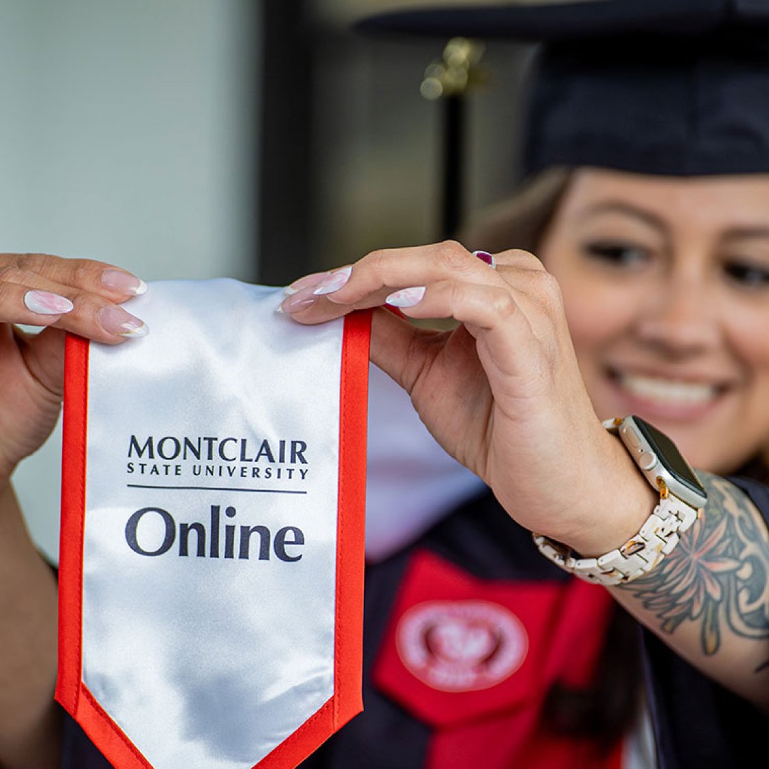 Online degree completion graduate wearing graduation gown and Montclair Online stole.