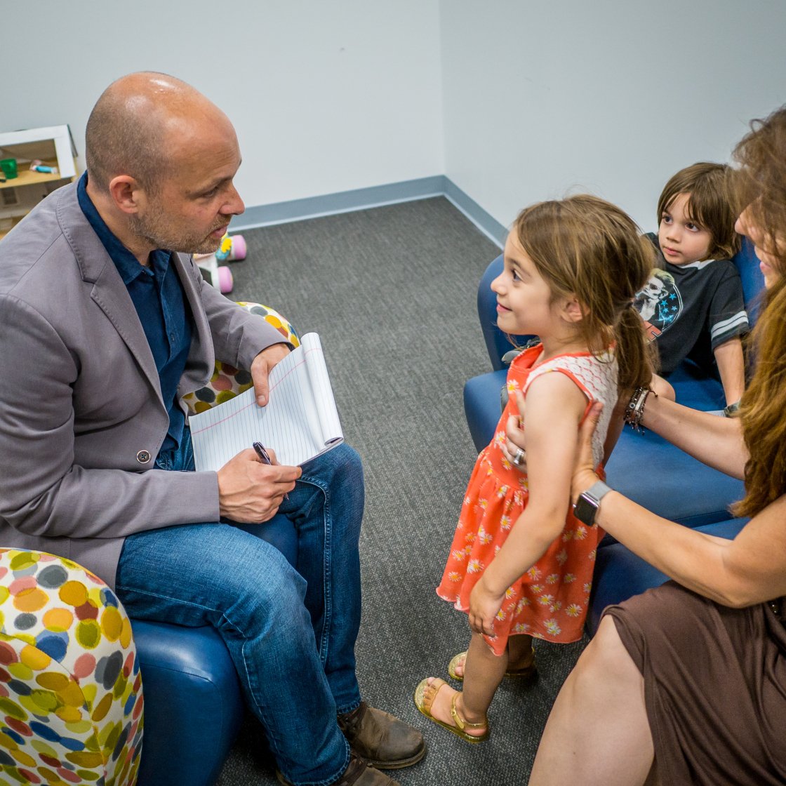 A faculty member interviews two young children and their parent.