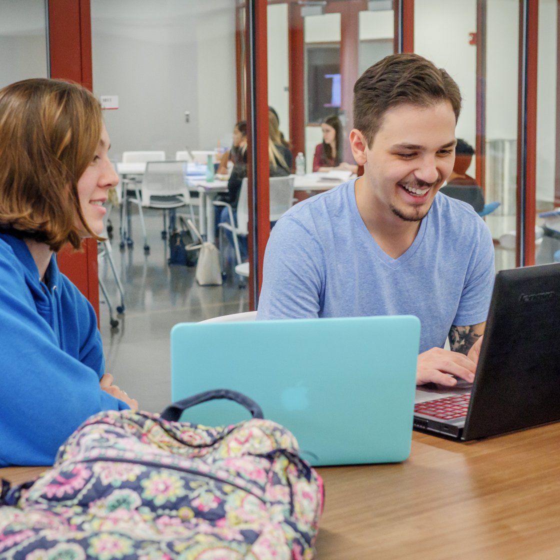 two students work at their laptops