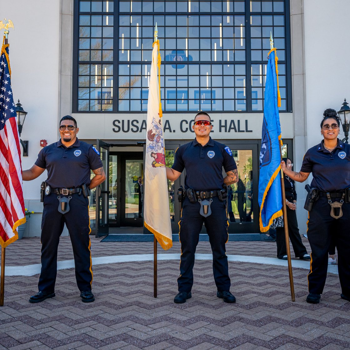 three officers holding flags at an event